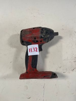 une perceuse rouge posée sur une surface blanche