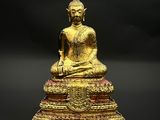 statue d'un Bouddha assis sur un socle, sur fond noir