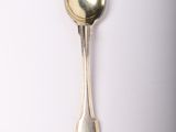 a silver spoon with a spoon handle on a white surface