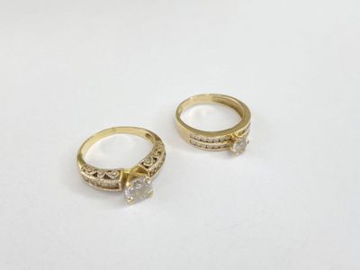 two gold rings with diamonds on them on a white surface