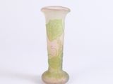 a glass vase with green leaves on it on a white surface