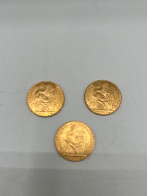 On voit trois pièces d'or sur une surface blanche