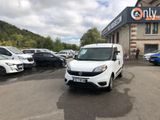 La camionnette blanche est garée devant un grand immeuble.