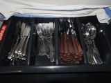a black tray with silverware and spoons in it