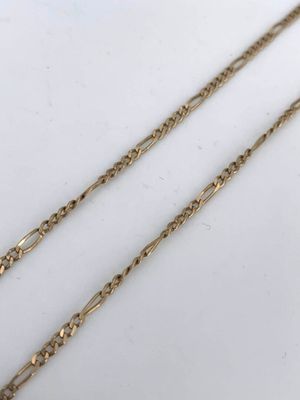 a close up of two gold chains on a white surface