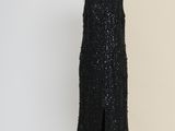 a black dress on a mannequin stand in front of a beige wall