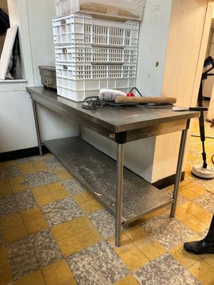 une personne debout dans une cuisine devant une grande table