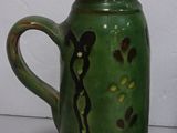 a green vase with a black design on it