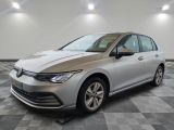 Une Volkswagen Golf argentée est garée sur un sol carrelé à damier.
