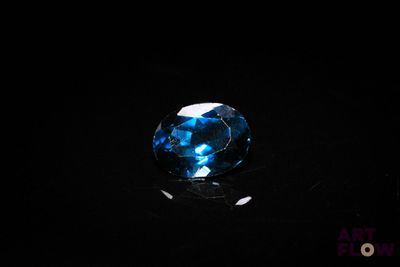 a close up of a blue diamond on a black surface