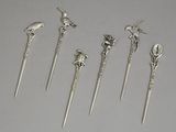 cinq cuillères en argent ornées d'oiseaux et de fleurs, posées sur une table