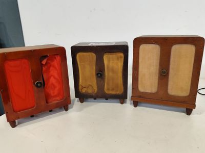 trois petites armoires en bois sont alignées sur une surface blanche