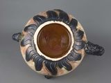 a brown and black vase sitting on a gray surface