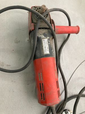 une perceuse rouge et noire posée par terre à côté de quelques fils électriques