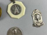 three silver and gold medals and a coin on a white surface