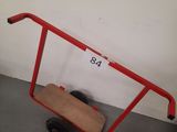 un chariot rouge sur lequel est posée une planche en bois, dans une pièce