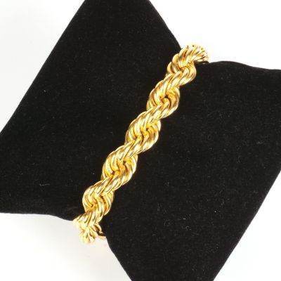 un gros plan d'un bracelet en or posé sur une serviette noire