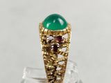 a close up of a ring with a green stone on it