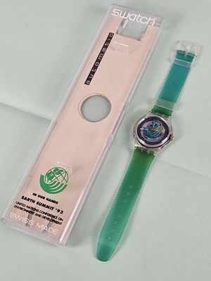a green watch sitting next to a clear watch case