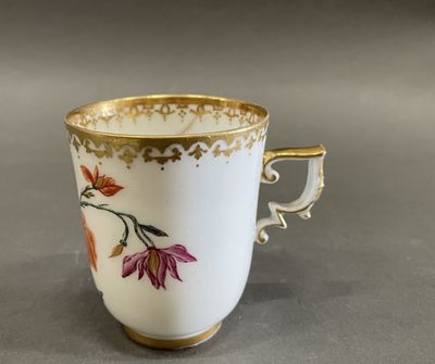 a white cup with a gold rim and a flower design on it