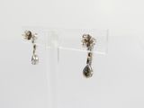 pair of silver earrings on clear acrylic stand against a white background