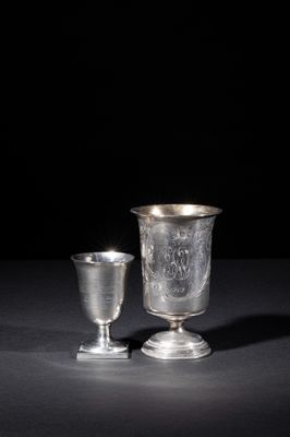 silver goblet and cup on a black surface with a black background