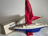 a small sailboat with a red sail on it