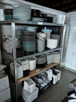 many plates and bowls stacked on a shelf in the kitchen