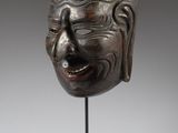 a wooden mask on a stand with a gray background