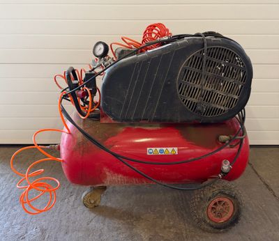 a red air compressor sitting on top of a cart