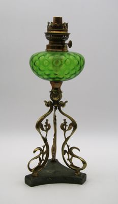 une lampe ancienne en verre vert avec un pied en métal, sur fond blanc