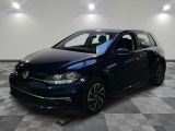 Une Volkswagen Golf bleue est garée dans une pièce au sol carrelé.
