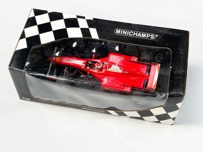une voiture de course rouge dans une boîte posée sur une surface blanche
