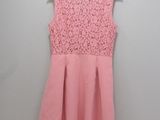 a pink dress hanging on a hanger against a wall