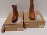 une paire de bottines en cuir marron posées sur une boîte en carton