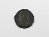 une vieille pièce de monnaie sur laquelle figure un visage, posée sur une surface blanche