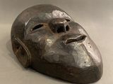 un masque métallique posé sur une table, sur fond blanc