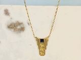 un collier plaqué or orné d'un motif géométrique sur une chaîne