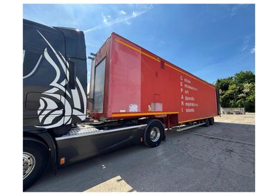 un semi-remorque avec une remorque rouge garé sur un parking