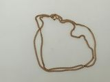 a close up of a gold necklace with a chain on a white surface