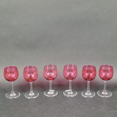 six verres à vin roses alignés sur une surface grise