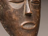 a close up of a wooden mask on a metal stand