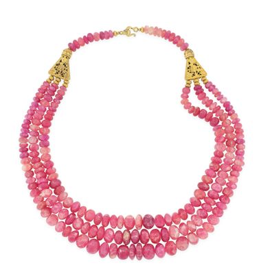 un collier à trois rangs de perles roses rehaussé de touches dorées