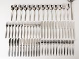 many forks and spoons laid out on a white surface