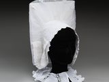 une tête de mannequin noire coiffée d'un chapeau blanc