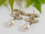 pair of earrings with pearls on a white surface next to a leaf