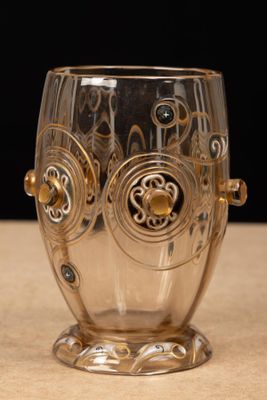 a glass cup that has a gold design on it
