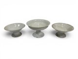 three bowls sitting on pedestals on a white surface