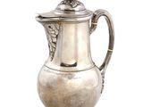 une cafetière ancienne en argent posée sur un support, sur fond blanc