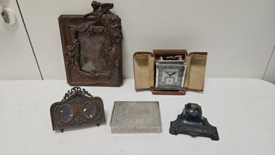 une table sur laquelle se trouvent une horloge, un cadre photo et d'autres objets